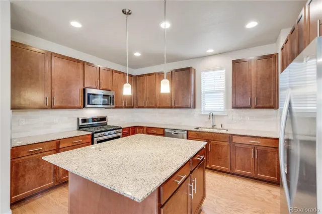 a kitchen with stainless steel appliances granite countertop a sink a stove and a refrigerator
