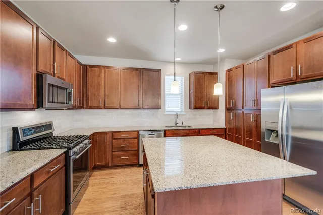 a large kitchen with stainless steel appliances granite countertop a sink refrigerator and cabinets
