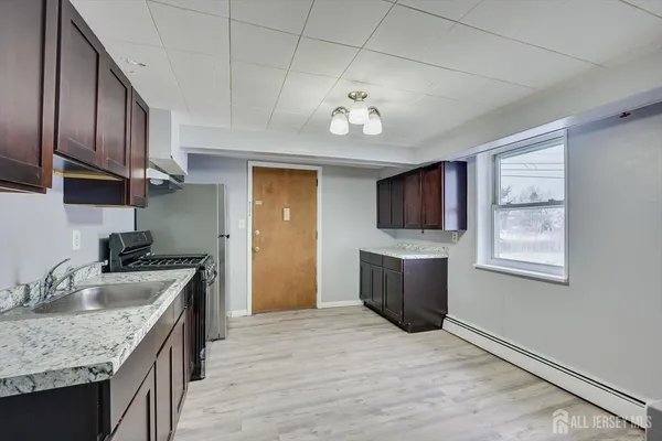 a view of kitchen with refrigerator and white cabinets