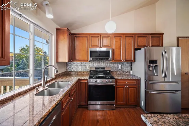 a kitchen with granite countertop a sink a counter space stainless steel appliances and cabinets