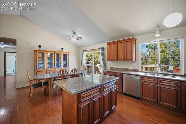 a kitchen with stainless steel appliances granite countertop a stove top oven a sink dishwasher and wooden cabinets with wooden floor