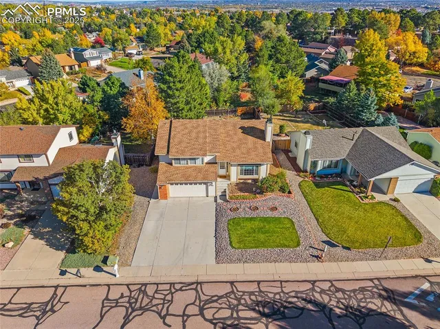 an aerial view of a house with swimming pool and large trees