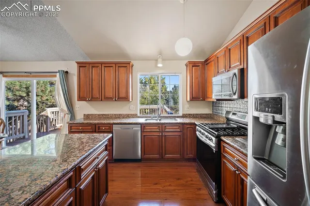 a kitchen with stainless steel appliances granite countertop sink stove top oven and refrigerator