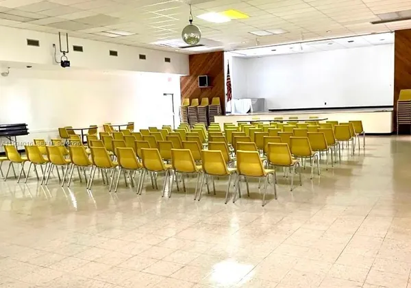 a living room with lots of tables a large window and chairs