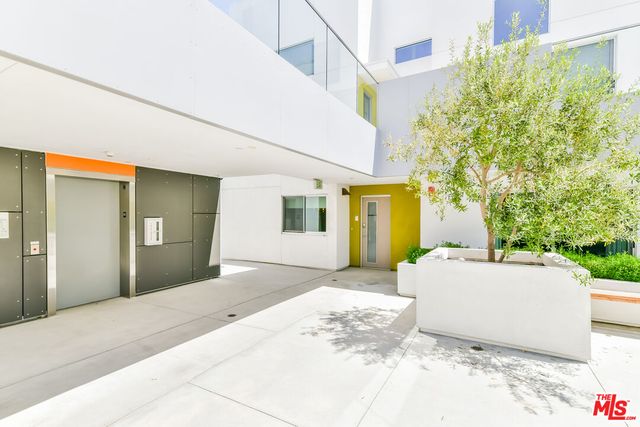 a view of a house with potted plants and a large tree