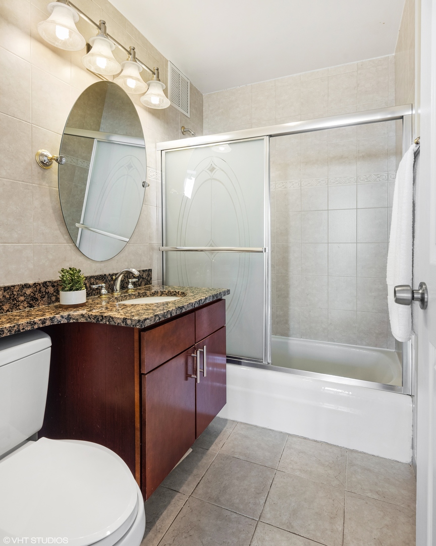 655 West Irving Park Road, Unit 5301 Chicago, IL 60613 - Photo 15 of 20 a bathroom with a granite countertop toilet sink and mirror
