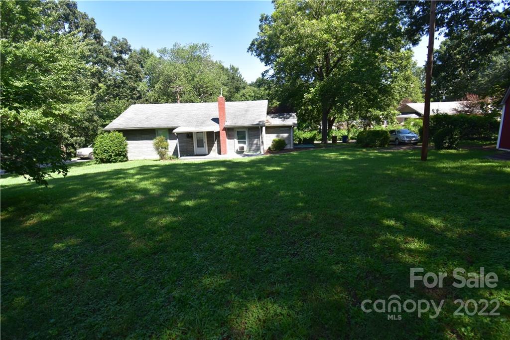a view of a big house with a big yard and large trees