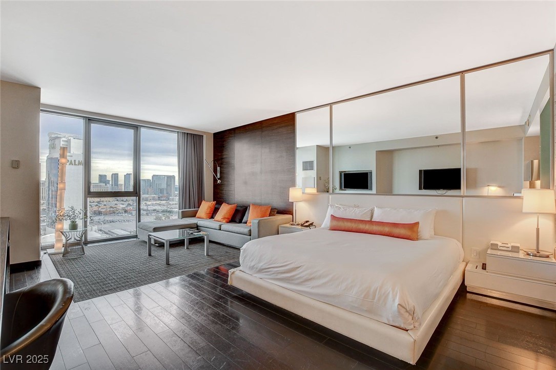 Bedroom with hardwood / wood-style flooring, floor to ceiling windows, and access to outside