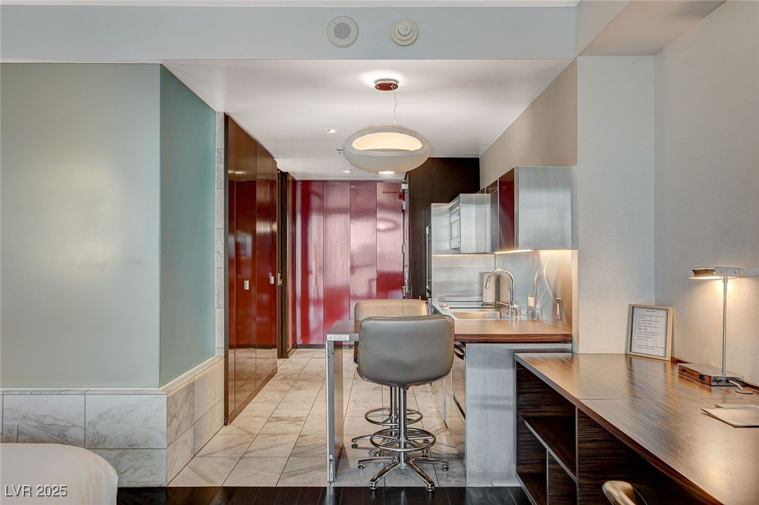 4381 West Flamingo Road, Unit 2204 Las Vegas, NV 89103 - Photo 13 of 27 Kitchen with light marble finish flooring, hanging light fixtures, and a breakfast bar