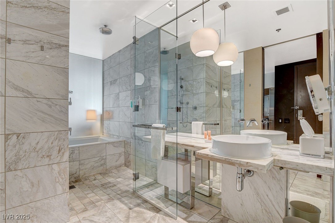 4381 West Flamingo Road, Unit 2204 Las Vegas, NV 89103 - Photo 19 of 27 Full bath featuring a stall shower, tile walls, and a bath
