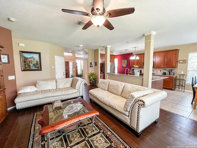 a living room with furniture kitchen view and a wooden floor