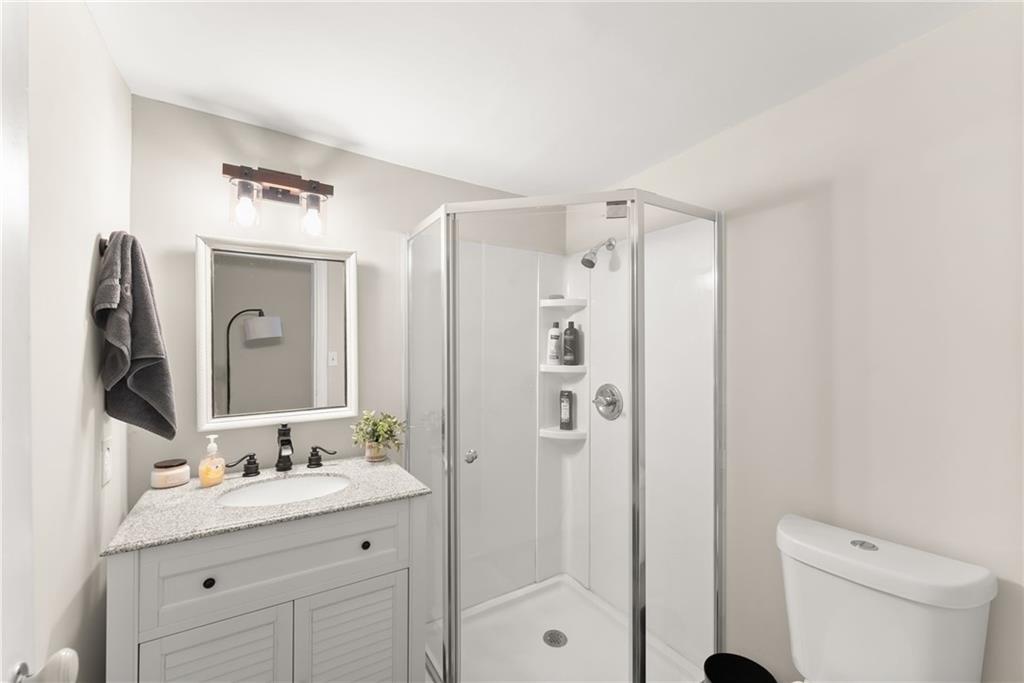 1519 New Hope Church Road Loganville, GA 30052 - Photo 26 of 48 a bathroom with a granite countertop sink toilet a mirror a vanity and shower