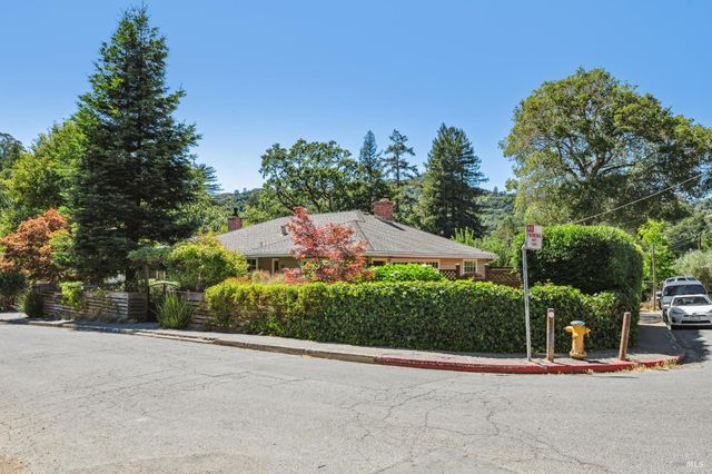 a view of a garden with a bench in front of the house
