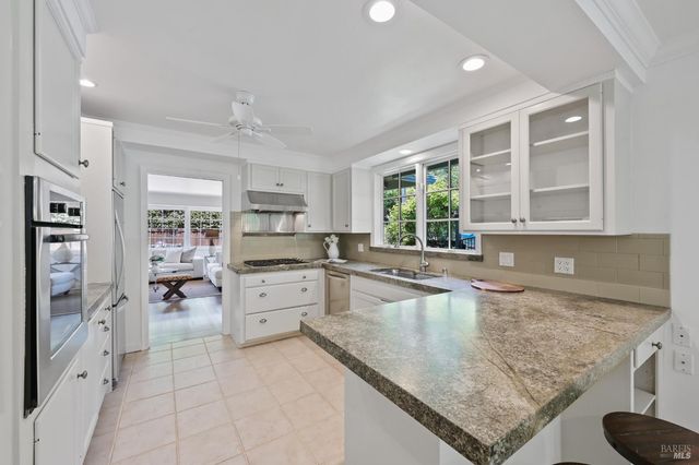 a large kitchen with granite countertop a large window and white cabinets