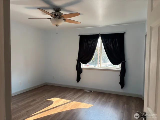 a view of a hallway with wooden floor and cabinet