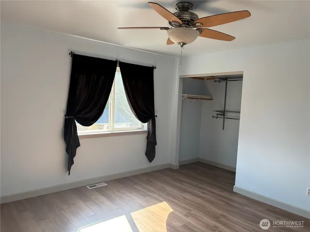 a view of a room with wooden floor staircase and a ceiling fan