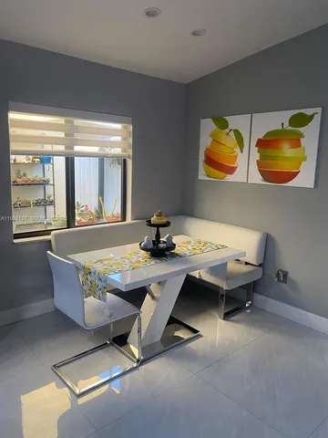 a living room with table chairs and wooden floor
