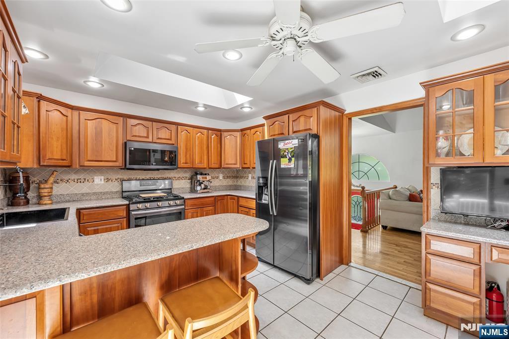 21 Marcia Road Ringwood, NJ 07456 - Photo 14 of 42 a kitchen with stainless steel appliances granite countertop a refrigerator a sink a stove top oven and a dining table with wooden floor
