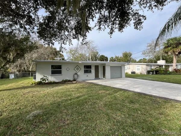 a front view of a house with a yard and trees