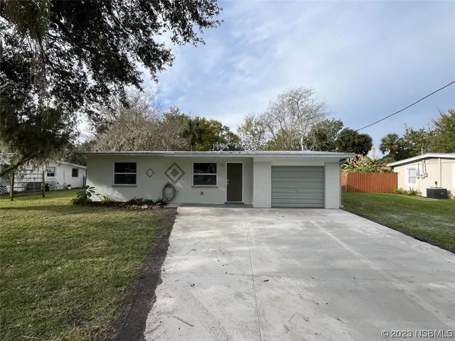 a front view of house with yard and trees in the background