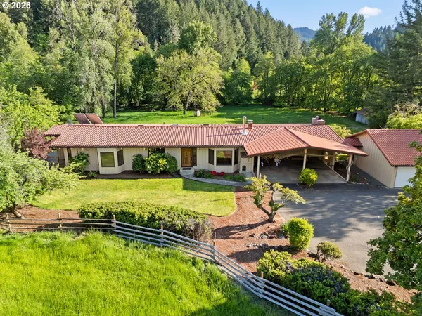 an aerial view of a house with swimming pool and large trees