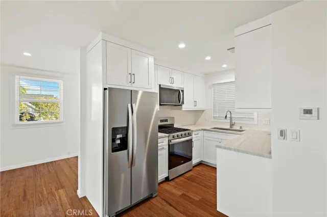 a kitchen with stainless steel appliances white cabinets and a stove a oven with wooden floor