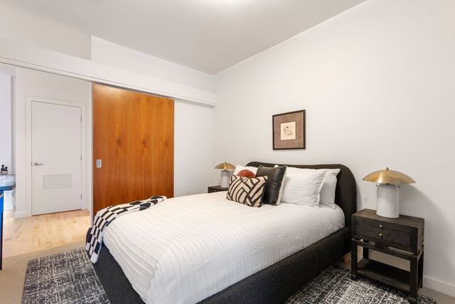 a bedroom with a bed and a lamp on dresser