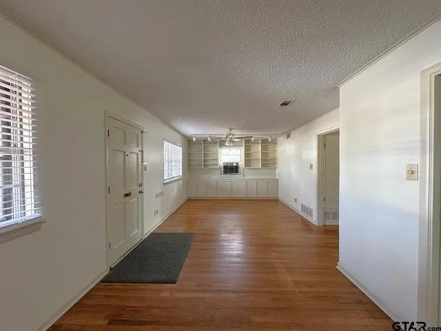 a view of an empty room with wooden floor and windows