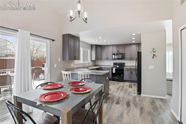 a kitchen with stainless steel appliances granite countertop a sink a stove a refrigerator cabinets and dining table