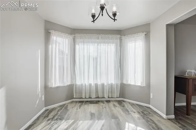 an empty room with wooden floor cabinet and windows