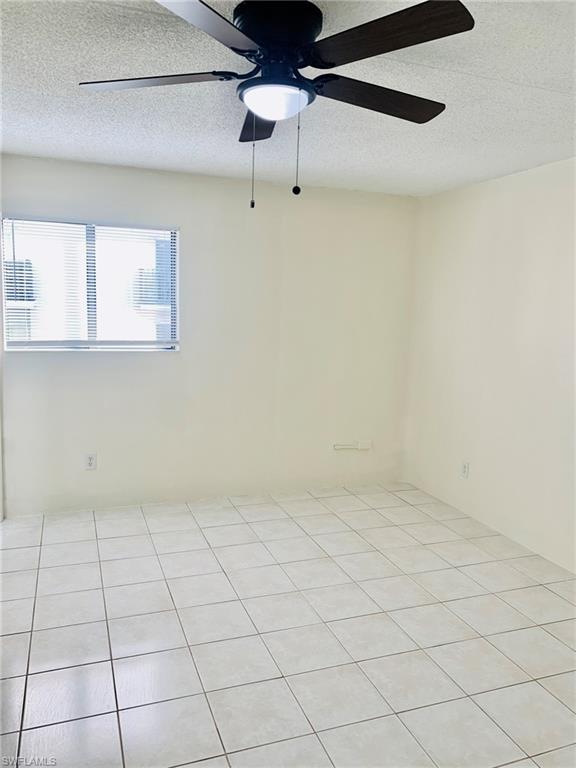 826 Wiggins Pass Road, Unit 214 Naples, FL 34110 - Photo 15 of 21 Empty room with a textured ceiling, a ceiling fan, and light tile patterned floors