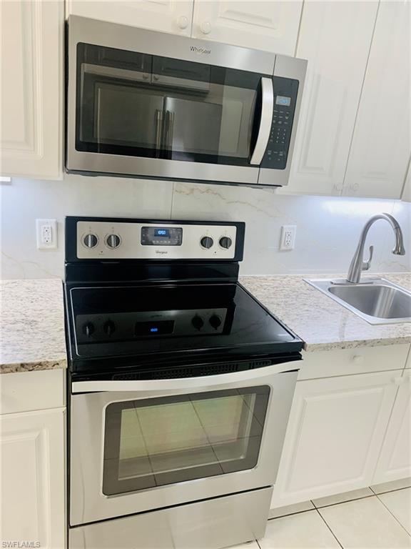 826 Wiggins Pass Road, Unit 214 Naples, FL 34110 - Photo 8 of 21 Kitchen featuring appliances with stainless steel finishes, white cabinetry, and decorative backsplash