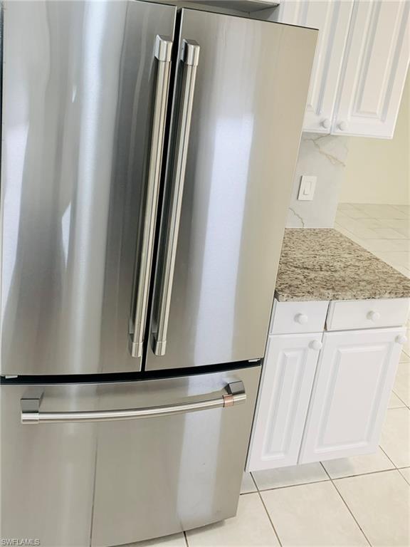 826 Wiggins Pass Road, Unit 214 Naples, FL 34110 - Photo 10 of 21 Kitchen view of high end refrigerator, white cabinets, and light stone counters