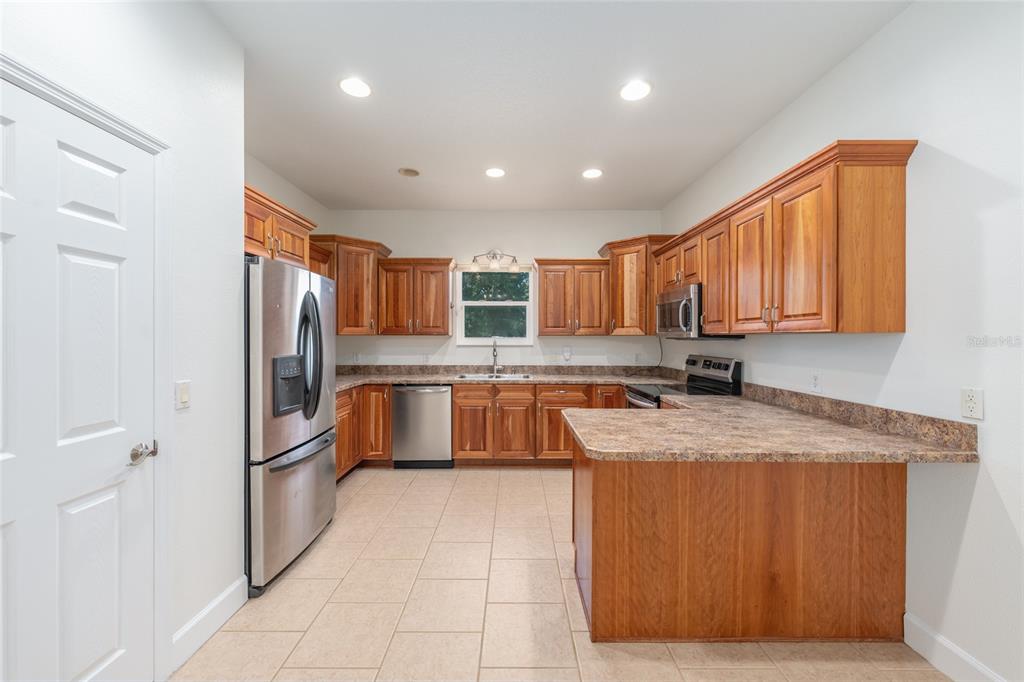 4735 Southeast 112th Street Road Belleview, FL 34420 - Photo 25 of 73 a large kitchen with granite countertop a sink refrigerator and cabinets