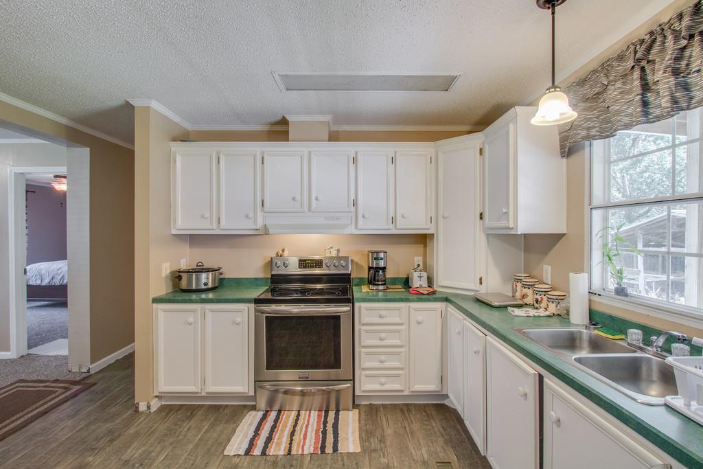 4035 Rock Springs Road Watertown, TN 37184 - Photo 10 of 26 a kitchen with stainless steel appliances granite countertop a stove a sink dishwasher and white cabinets with wooden floor