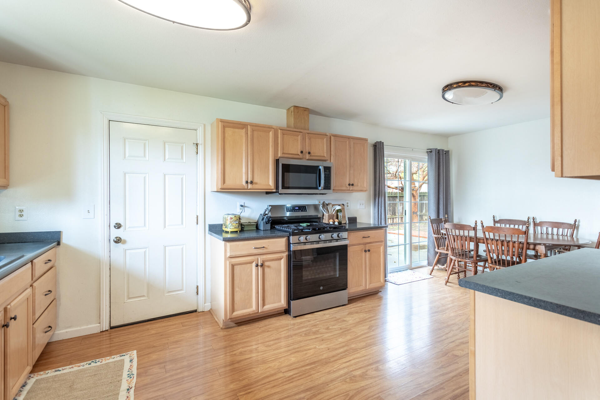 910 Aloha Street Red Bluff, CA 96080 - Photo 5 of 26 a kitchen with granite countertop a stove top oven a sink dishwasher and a refrigerator with wooden floor