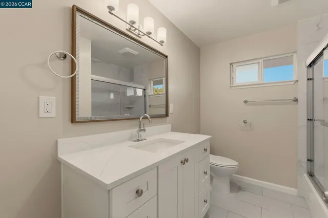 a bathroom with a sink a toilet a mirror and shower