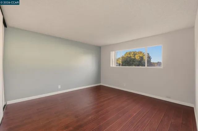 an empty room with wooden floor and window