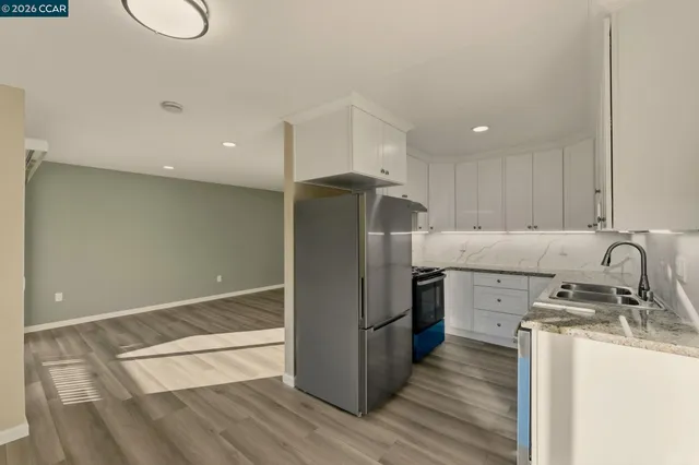 a kitchen with stainless steel appliances granite countertop a refrigerator a stove and a sink with wooden floor