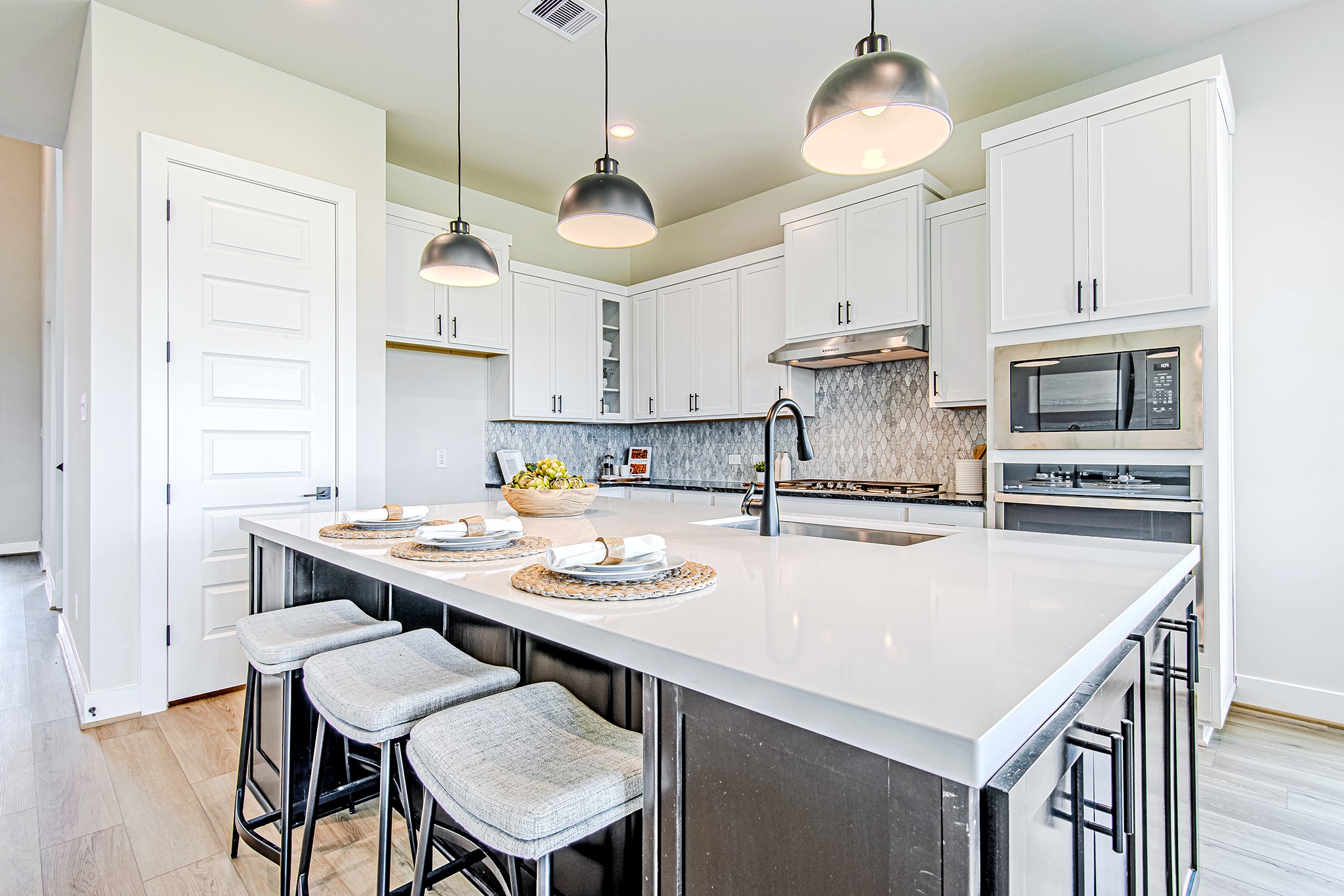 141 Peninsula Point Drive Montgomery, TX 77356 - Photo 10 of 47 A modern culinary dream—this kitchen features a spacious island with seating, matte black hardware, and a sophisticated backsplash that adds texture and elegance.