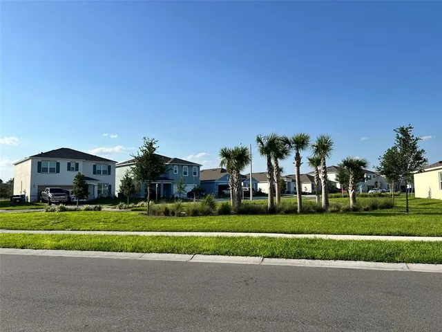 a view of a house with a big yard and palm trees