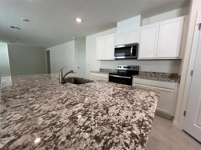 a kitchen with stainless steel appliances granite countertop a stove a sink and a refrigerator