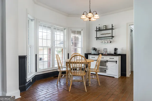 a dining room with wooden floor a chandelier a wooden table and chairs