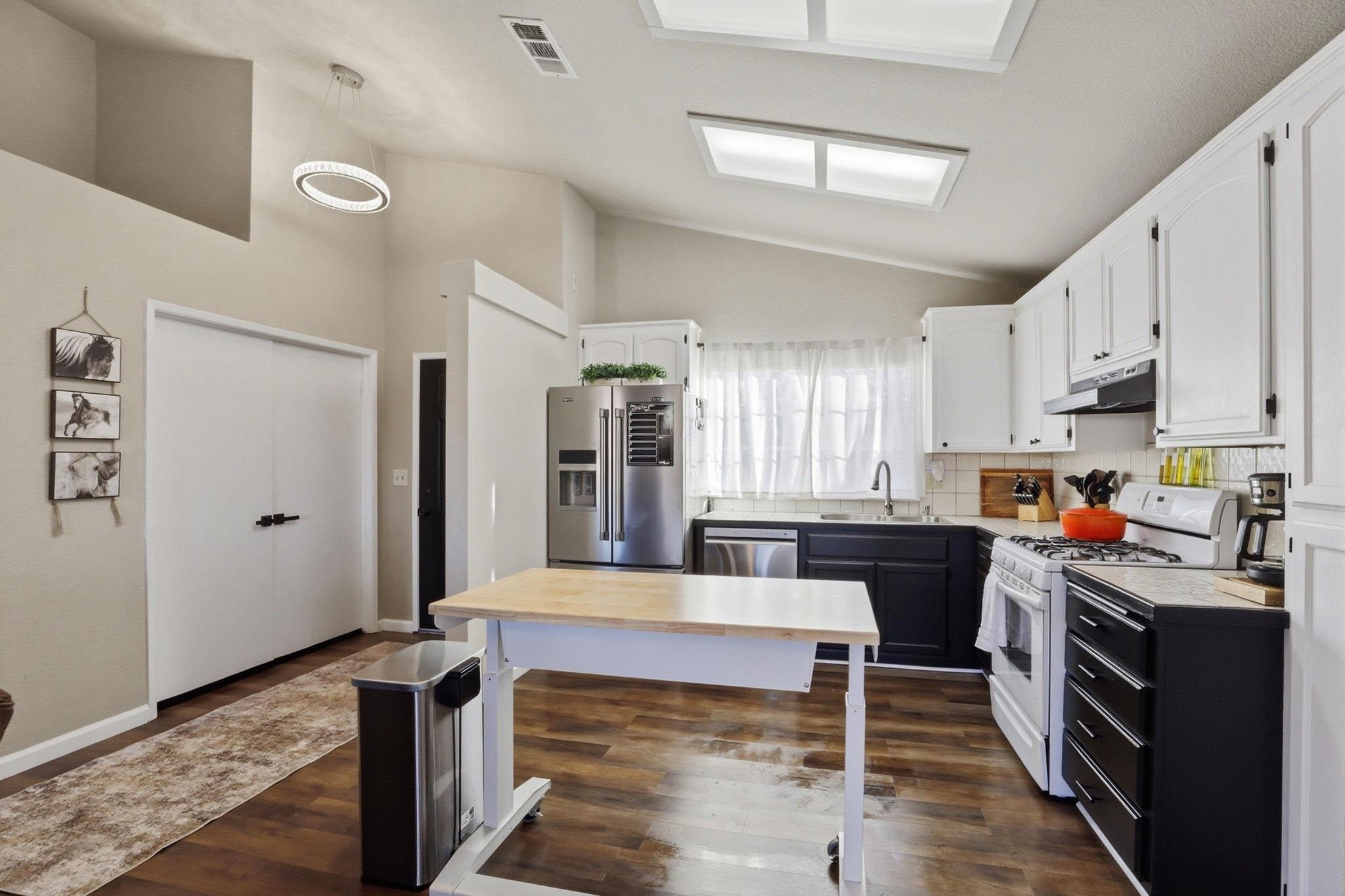 799 Morgans Ranch Circle Galt, CA 95632 - Photo 12 of 36 Dual tone kitchen featuring stainless steel appliances, two tone cabinetry, light countertops, lofted ceiling, and tasteful backsplash