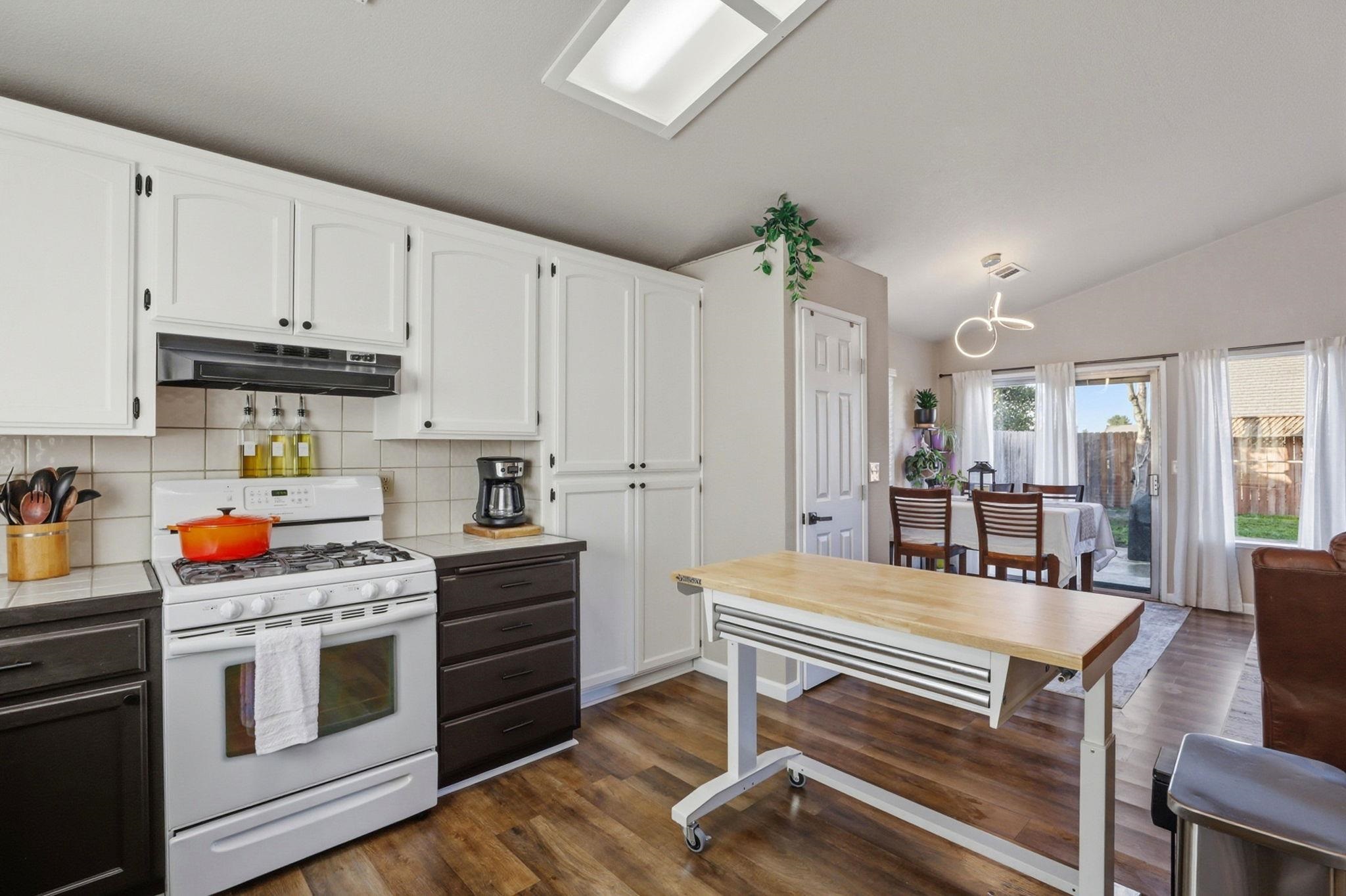 799 Morgans Ranch Circle Galt, CA 95632 - Photo 13 of 36 Kitchen featuring white range with gas cooktop, dual tone cabinets, tile countertops, tasteful backsplash, and lofted ceiling
