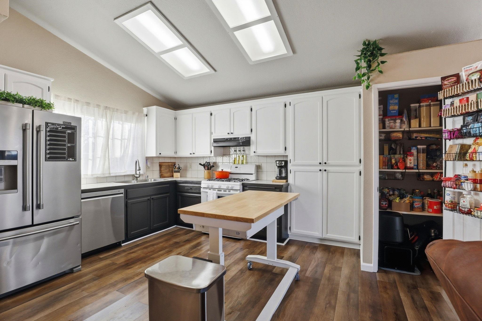 799 Morgans Ranch Circle Galt, CA 95632 - Photo 14 of 36 Dual tone kitchen with stainless steel appliances, two tone cabinetry, dark wood-style flooring, tasteful backsplash, and lofted ceiling