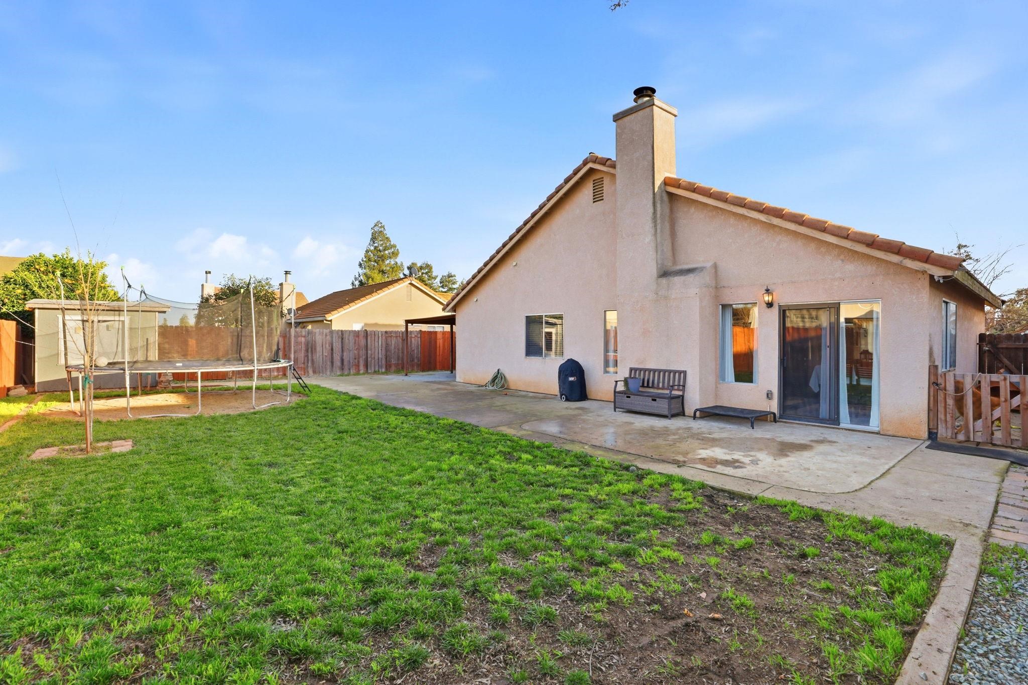 799 Morgans Ranch Circle Galt, CA 95632 - Photo 32 of 36 Back of house featuring a patio area, a trampoline, stucco siding, and a fenced backyard