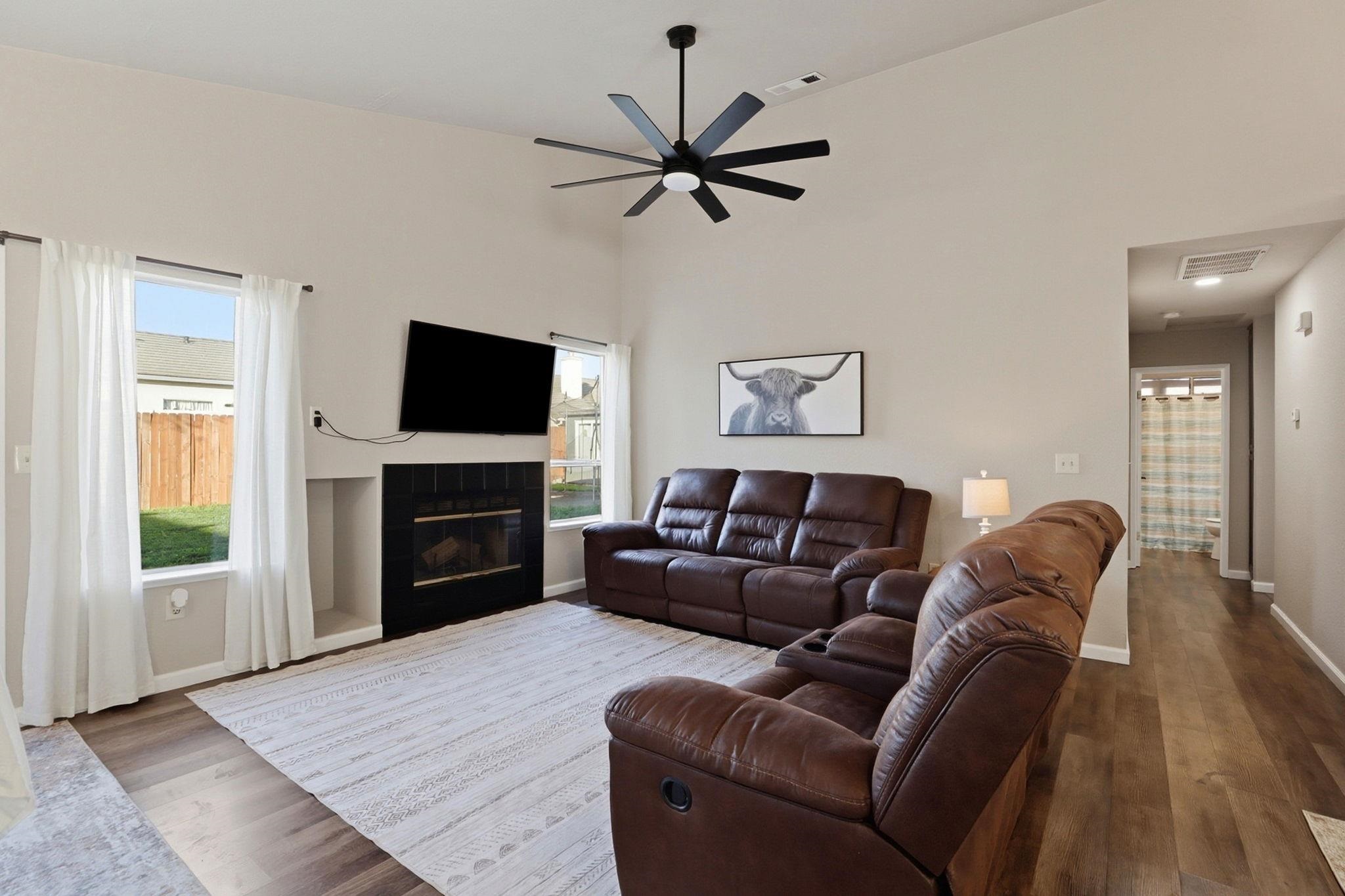 799 Morgans Ranch Circle Galt, CA 95632 - Photo 6 of 36 Living area with a fireplace, wood finished floors, ceiling fan, plenty of natural light, and a high ceiling