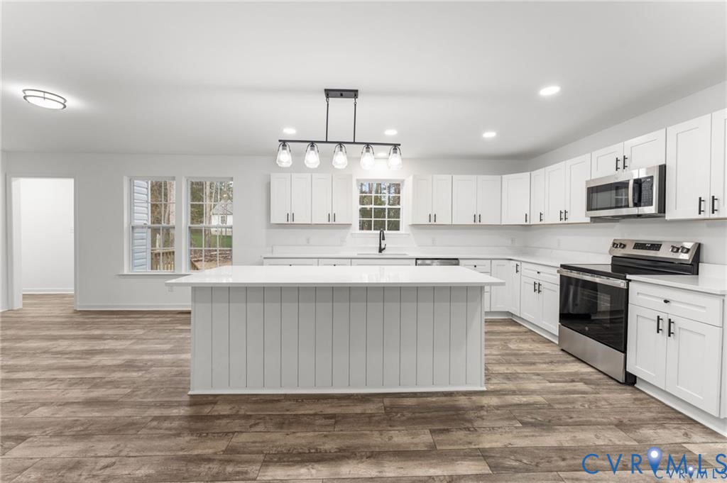 302 Musket Drive Ruther Glen, VA 22546 - Photo 6 of 27 a kitchen with kitchen island granite countertop a stove a sink a refrigerator and a microwave