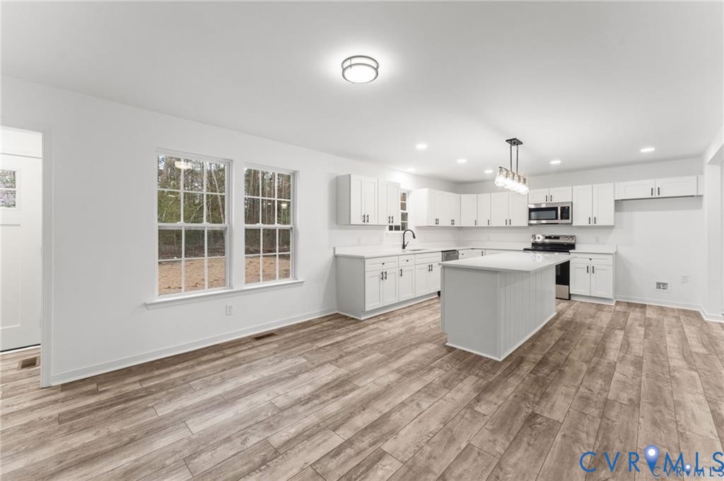 302 Musket Drive Ruther Glen, VA 22546 - Photo 10 of 27 a large white kitchen with kitchen island a stove a sink dishwasher and white cabinets with wooden floor